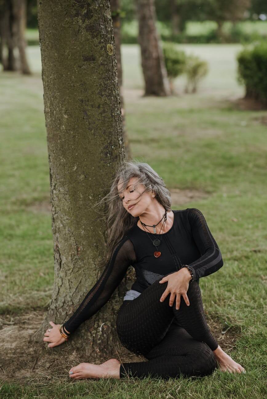 mindful woman performing seated twist pose near tree