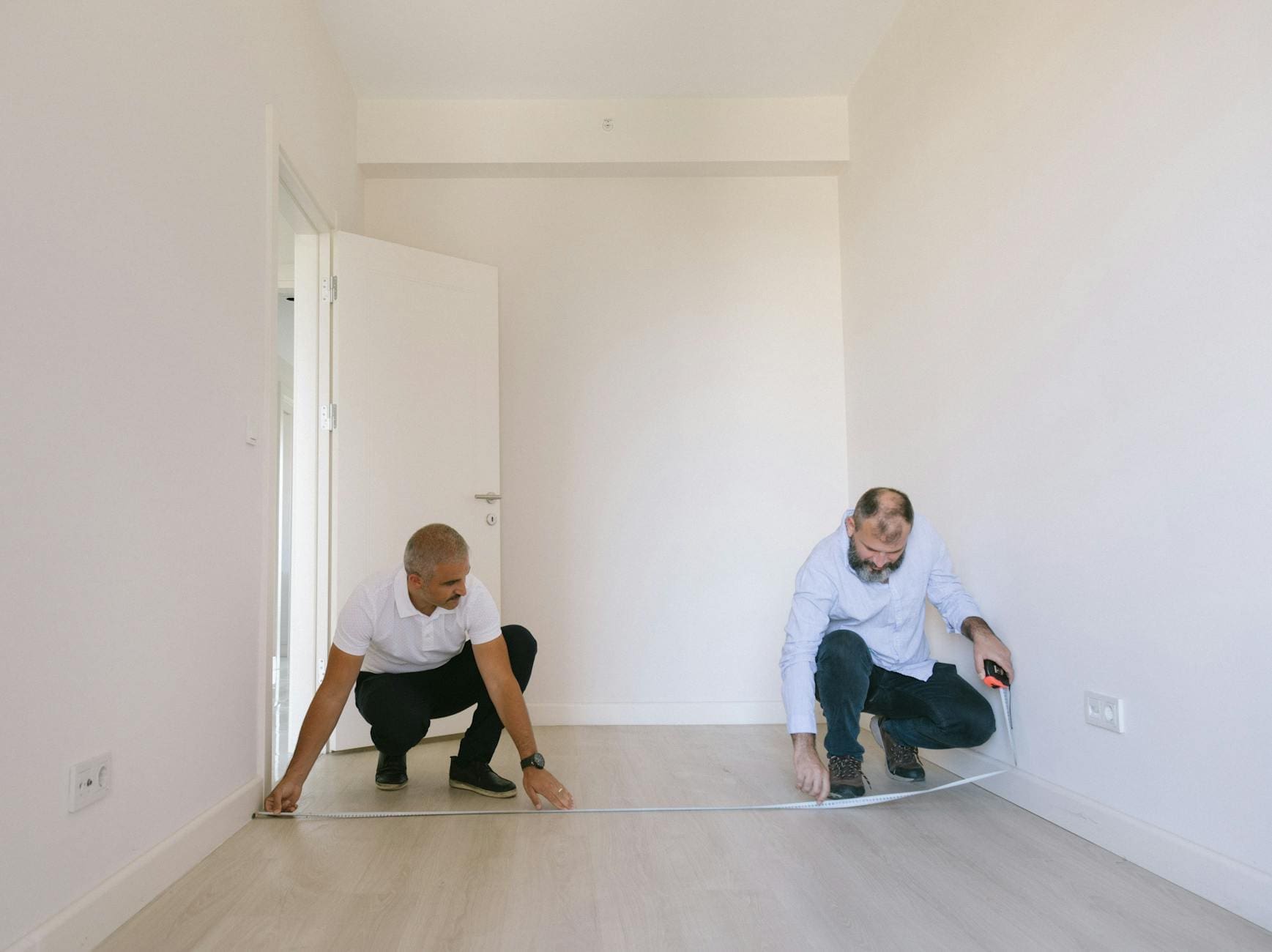 https://www.pexels.com/photo/two-men-measuring-length-of-the-empty-room-with-white-walls-8978578/