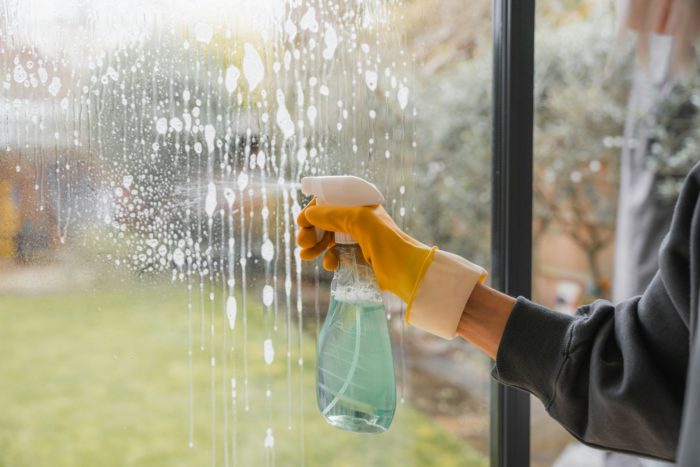 Person maintaining their balcony oasis by cleaning furniture and tending to plants.