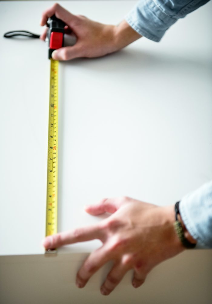 Person measuring balcony with a tape measure for accurate dimensions.