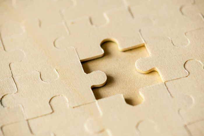 Close-up of a wooden puzzle with one missing piece, symbolizing problem-solving and completion.