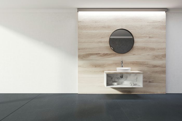 Elegant bathroom with a floating sink, wooden accent wall, and modern round mirror in a minimalist design.