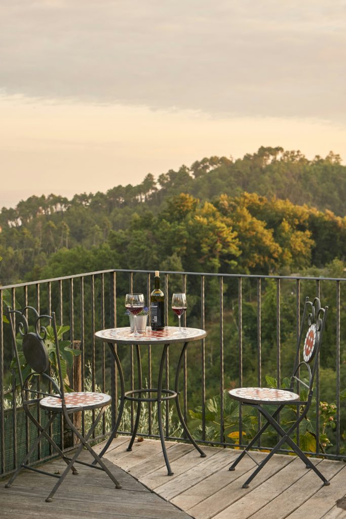 Tiny balcony transformed into a functional outdoor space with foldable furniture and a variety of plants in wall-mounted planters.