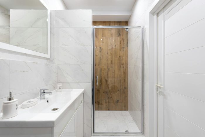 Bright modern bathroom with white tiles and glass shower door. Clean, contemporary design.