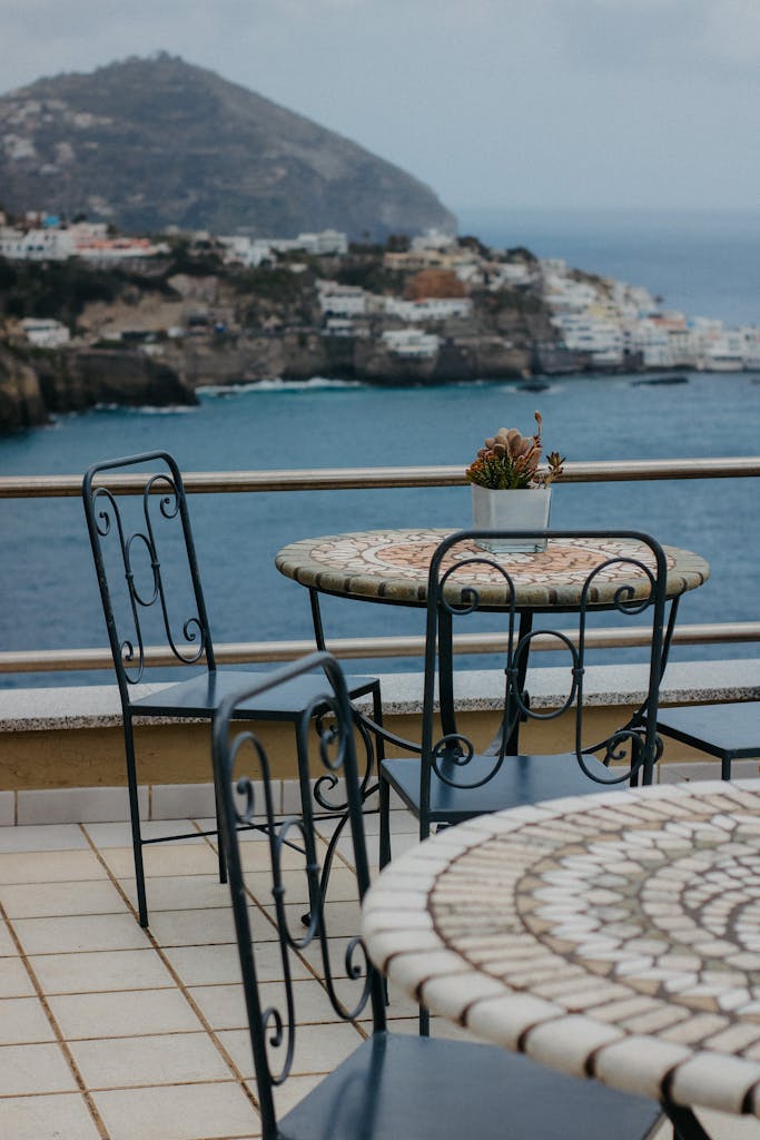Charming patio overlooking the sea with elegant tables and chairs, perfect for relaxing.