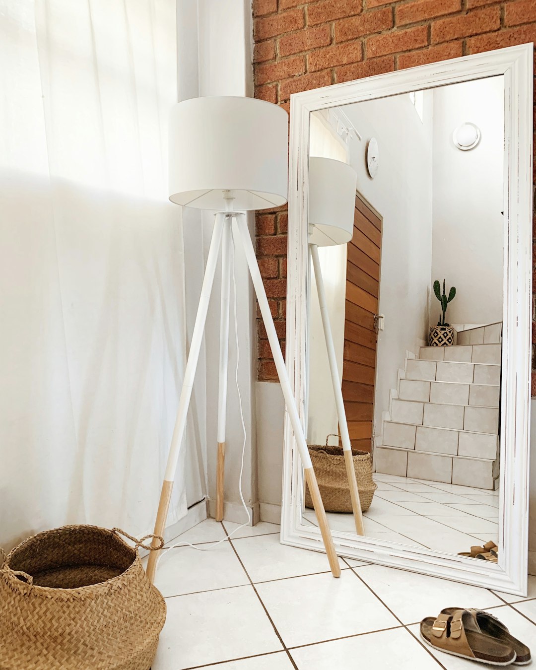 a room with a mirror, a lamp and a basket on the floor