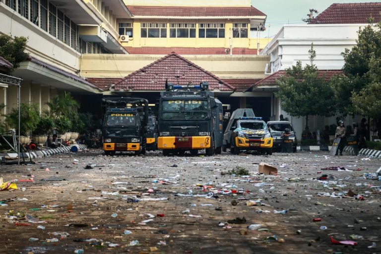 police vehicles parked in front of a building with trash on pavement