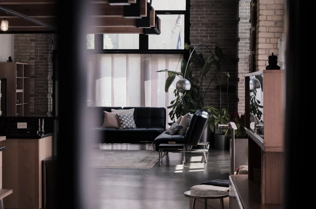 Industrial loft living room with double-height ceilings, exposed brick walls, black leather sofa and arc lamp