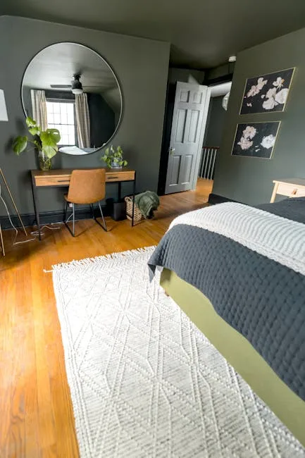 Small bedroom with wooden desk, round mirror, and