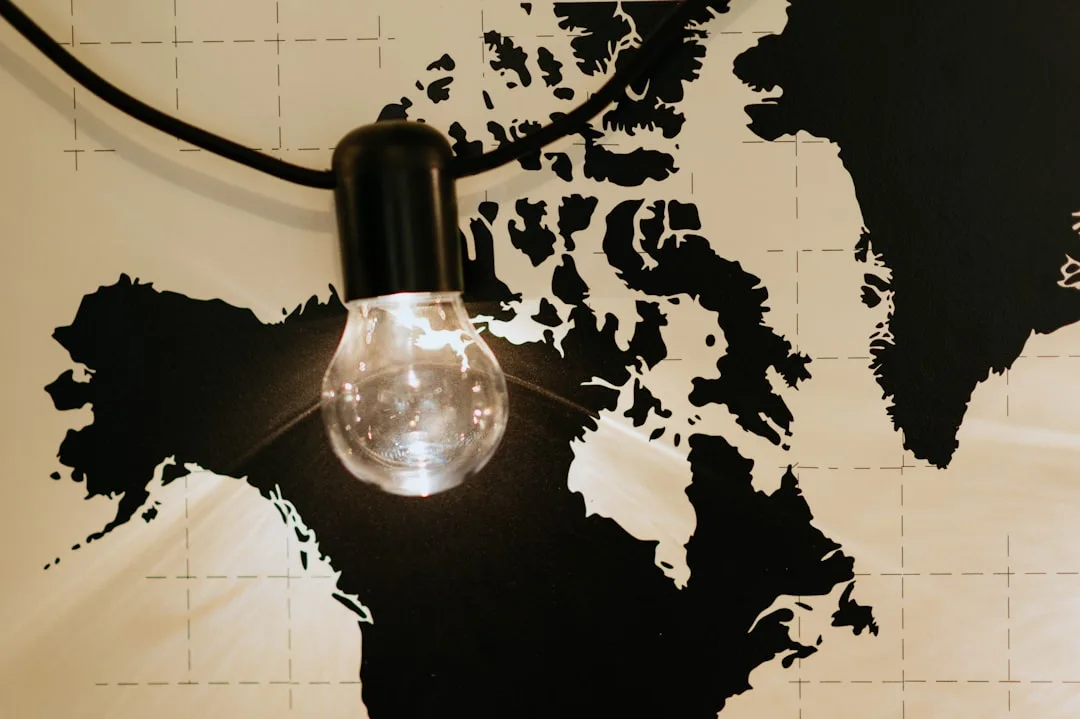 Glowing Edison bulb hanging in front of black and white world map wall art in rental apartment