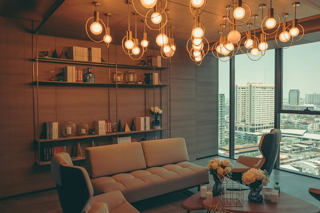 Modern living room with warm Edison bulb pendant lights, tufted sofa, and floor-to-ceiling city view windows