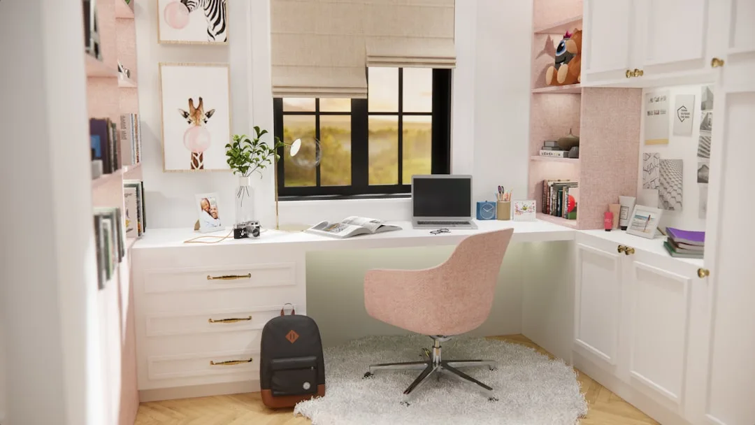 Small reach-in home office nook with white built-in desk, pink chair, shelving and laptop maximizing minimal depth space