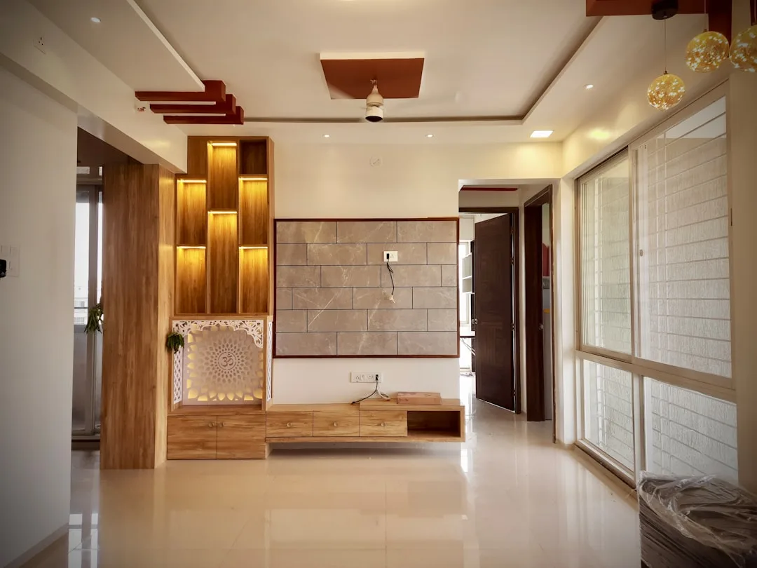 Indian living room with three-material palette: warm wood cabinetry, marble stone wall panel, and white walls