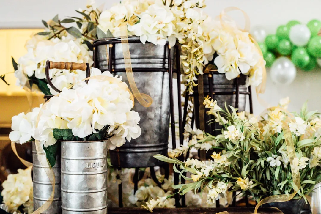 Vintage industrial metal buckets and galvanized cans filled with cream hydrangeas and gold ribbon floral arrangements
