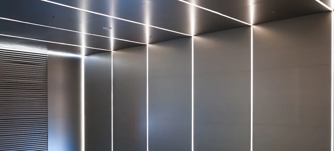 Modern interior wall with vertical LED strip lighting running floor to ceiling in a sleek silver paneled space