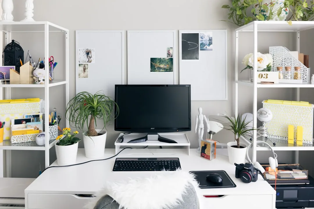 Organized small home office with white desk, dual shelving units, Acer monitor, plants, and neatly arranged stationery