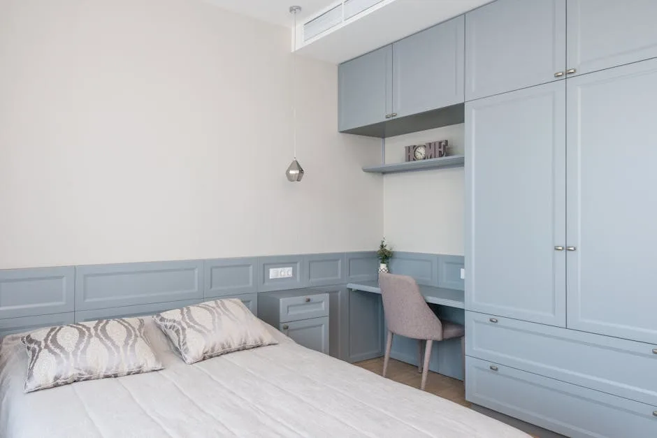 Built-in desk using dead corner space in bedroom with blue-grey cabinetry, open shelving, and integrated storage