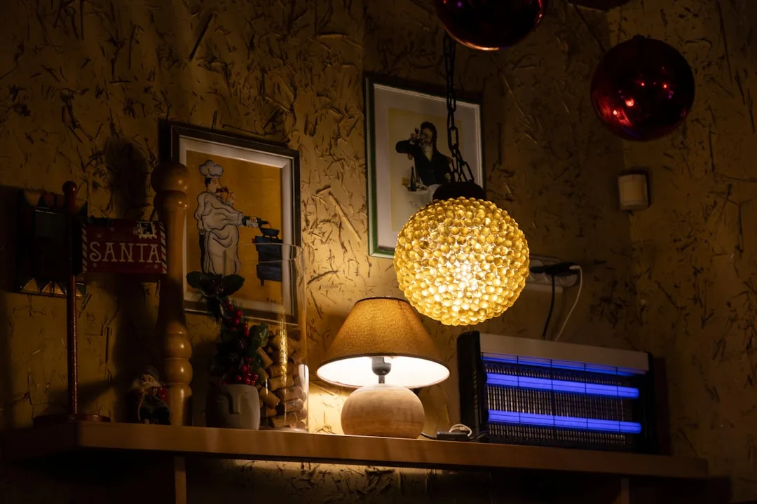 Warm holiday decor shelf with glowing pendant lamp, table lamp, and blue bug zapper light in cozy restaurant corner