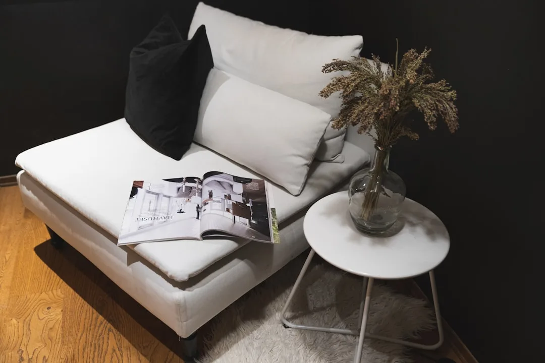 White chaise sectional sofa with black pillow and open magazine in a modern minimalist living room