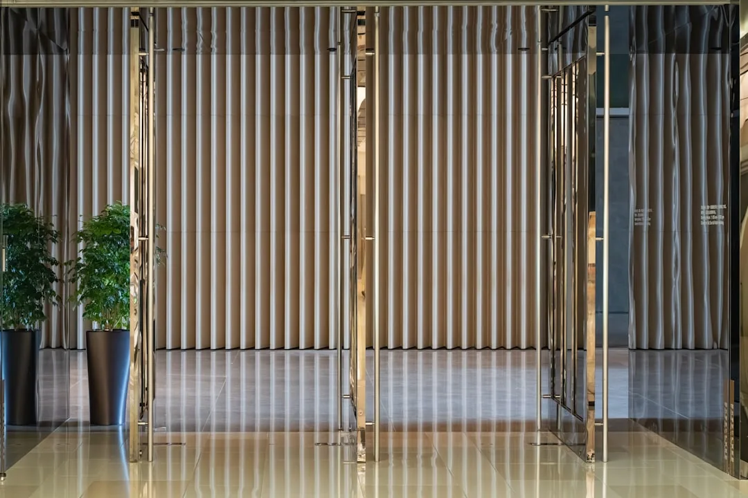 Floor-to-ceiling vertical ribbed curtain panels with gold metal frames in a modern lobby interior