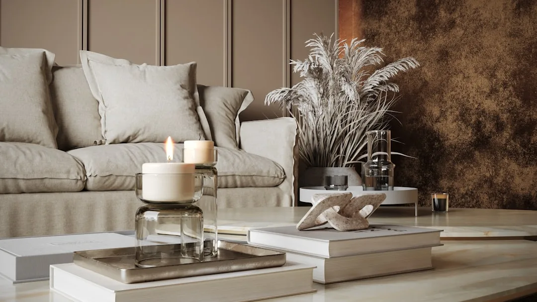 Textured linen sofa with layered coffee table styling featuring lit candles, stacked books, and dried pampas grass