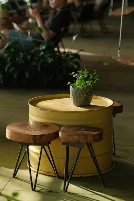 Repurposed yellow drum barrel used as a low side table with rustic wooden stools on metal hairpin legs