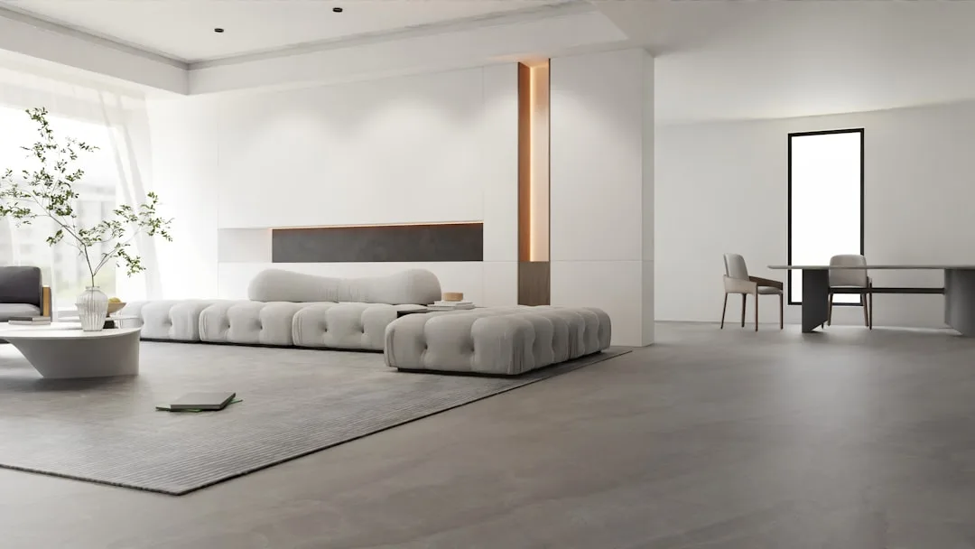 Minimalist Japanese-inspired living room with low tufted gray sofa, concrete floors, and clean white walls
