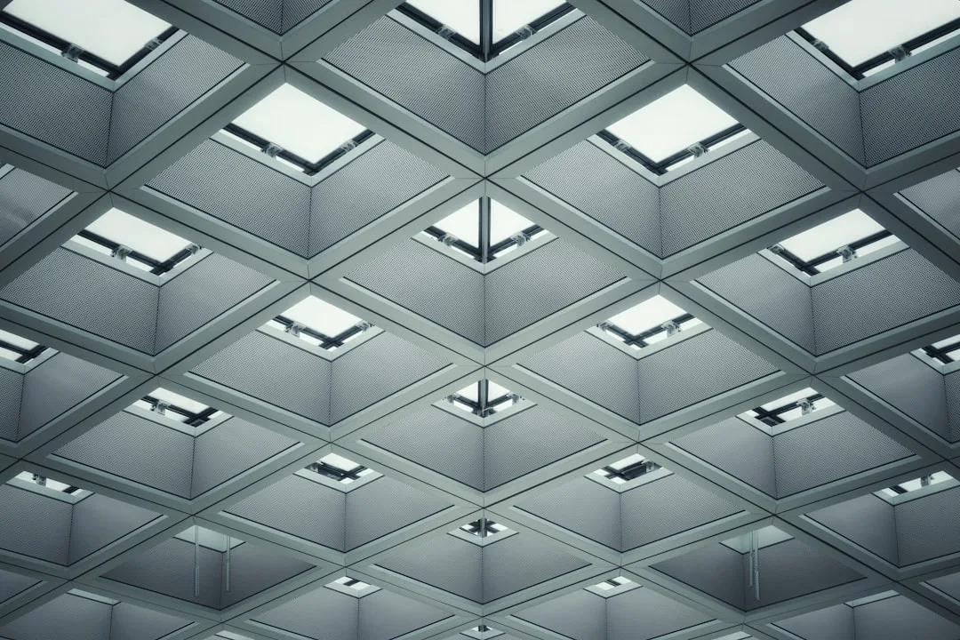 Modern geometric ceiling with skylights and recessed lighting panels creating bright, spacious architectural illusion