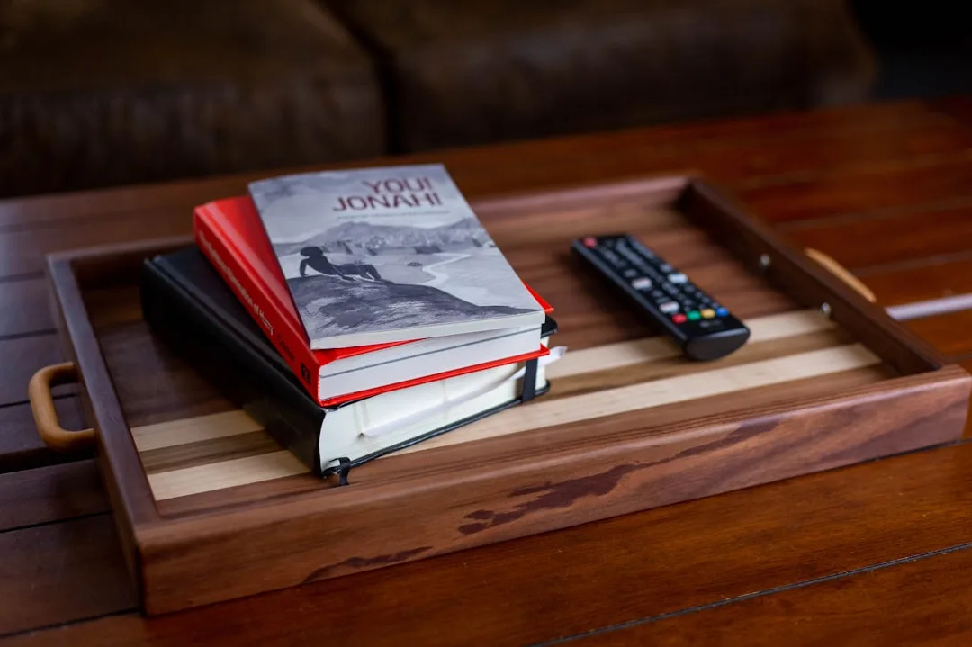 Wooden decorative tray with stacked books and TV remote on coffee table creating a signature tray moment