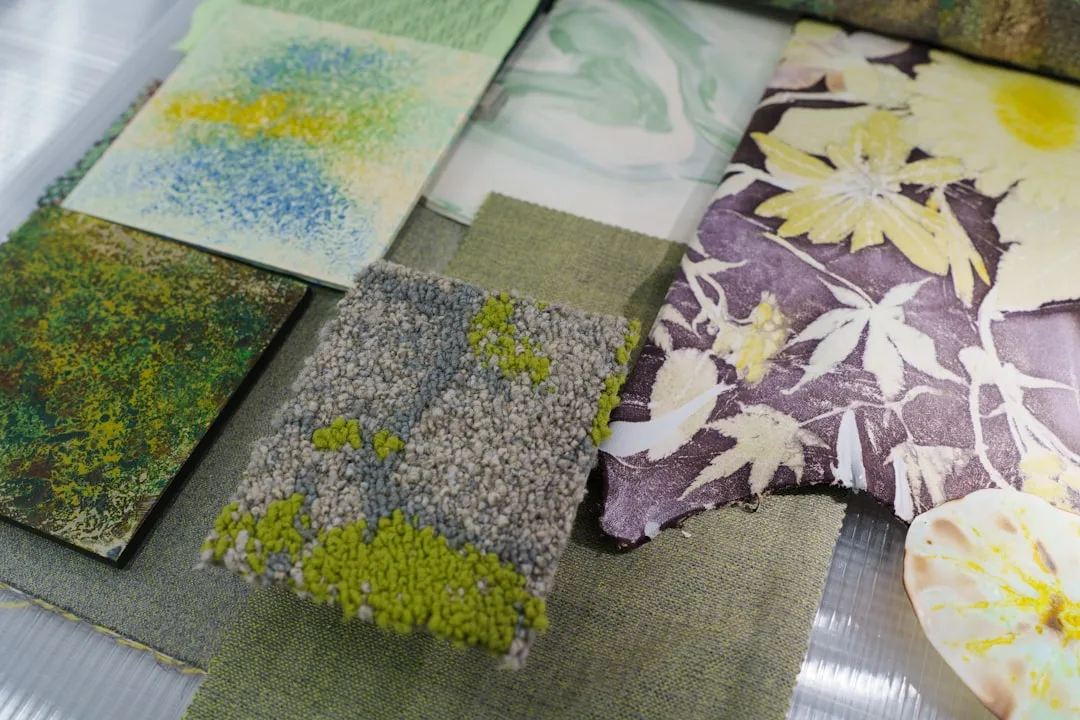 Layered textile swatches in green, purple, and floral patterns for interior design mood board