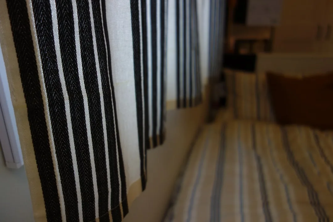 Black and white striped curtains hanging in a rental apartment hallway with striped carpet below