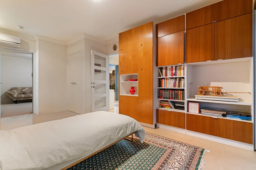 Murphy bed with built-in wooden wardrobe and bookshelf storage system in a multifunctional bedroom