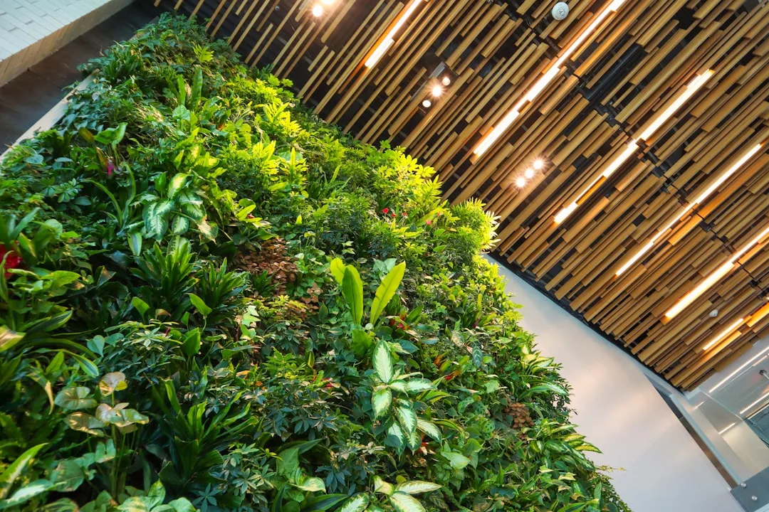 Lush vertical green wall with diverse tropical plants inside a modern interior with wooden ceiling and warm lighting