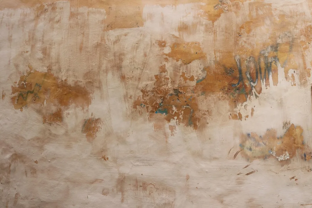 Weathered wall with layered textures showing peeling paint, rust tones, and teal accents over plaster base