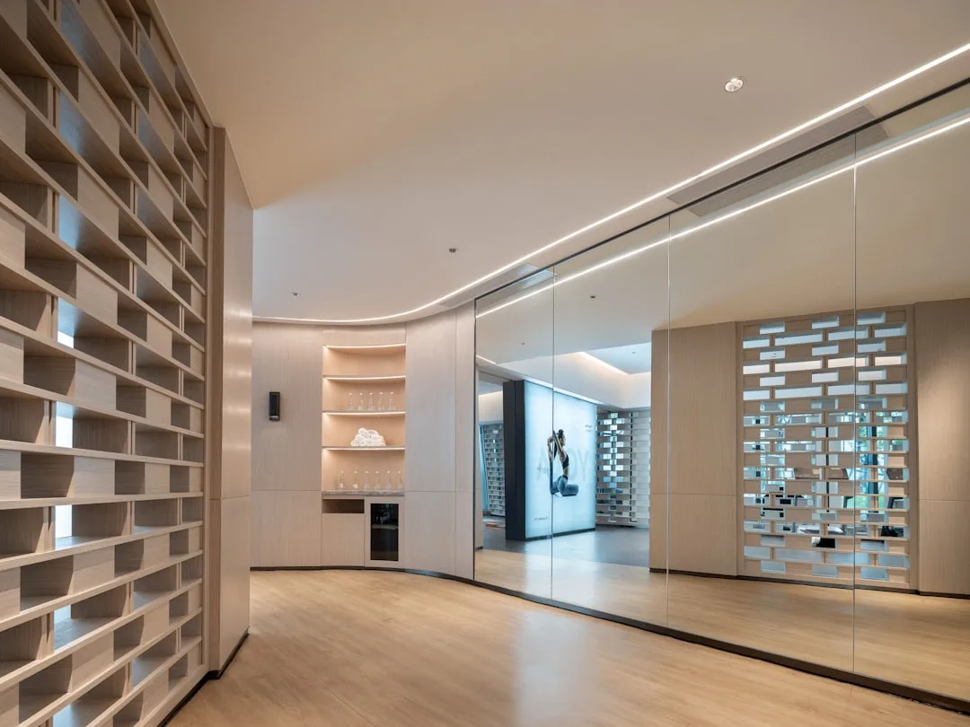 Floor-to-ceiling mirrors on curved wall expanding modern interior space with wood flooring and recessed lighting