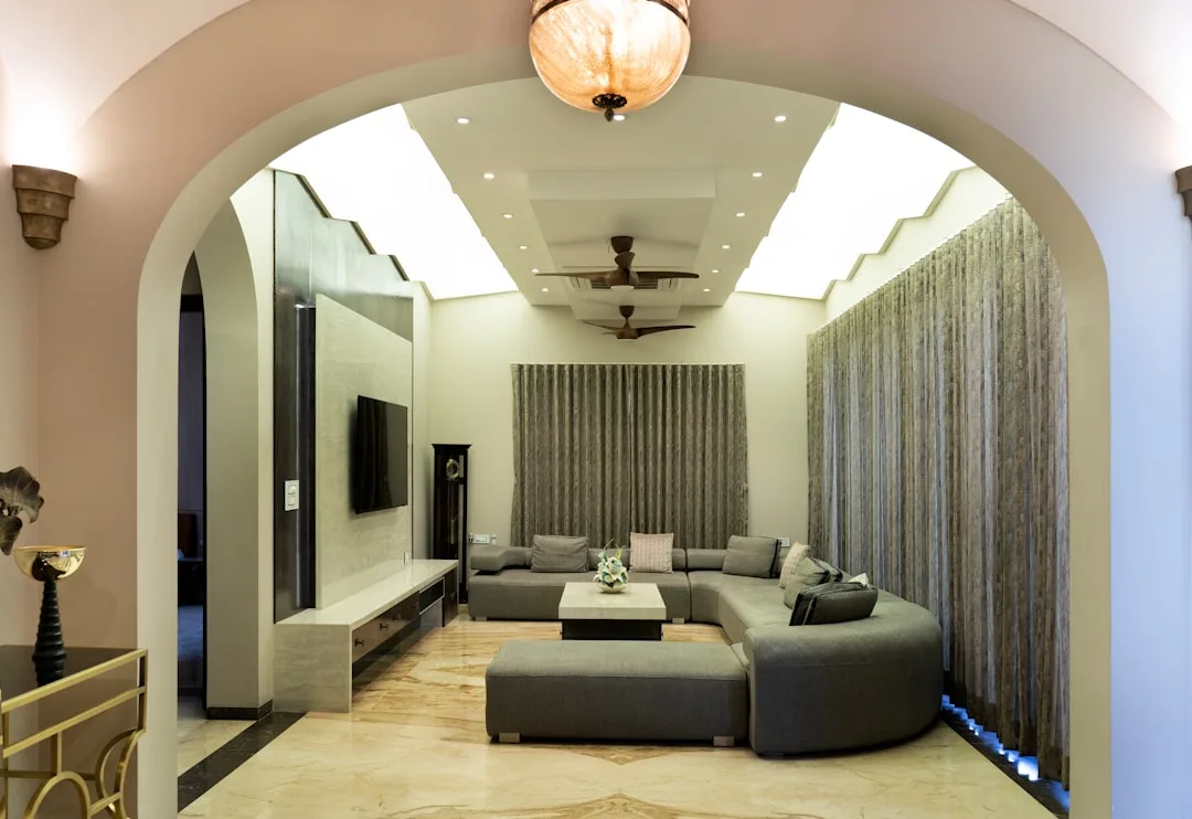 Large curved gray sectional sofa in reversed U-shape orientation filling a luxury living room with arched entryway