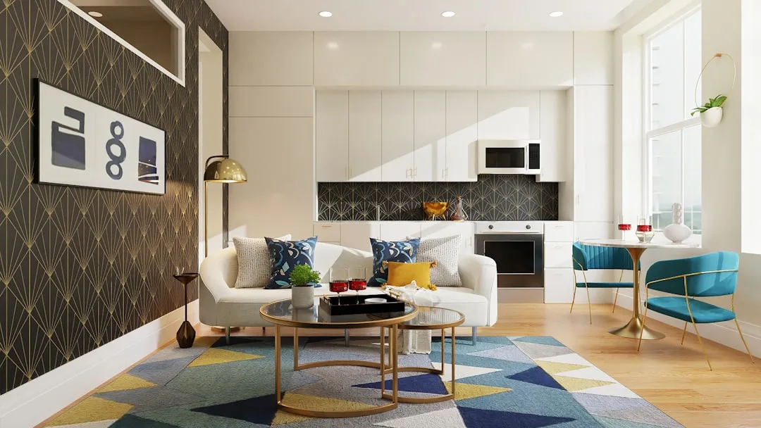 Modern living room with blue patterned throw pillows on white sofa, colorful geometric rug, and gold accent coffee table