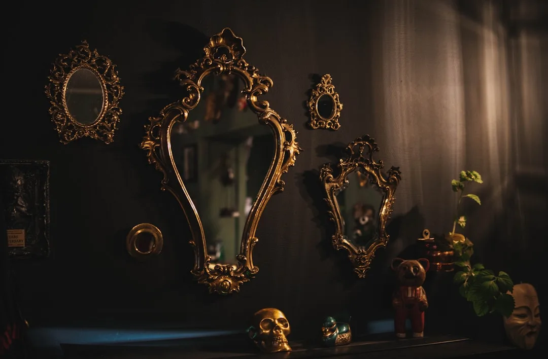 Collection of ornate gold baroque mirrors on dark wall with decorative objects doubling room decor visually