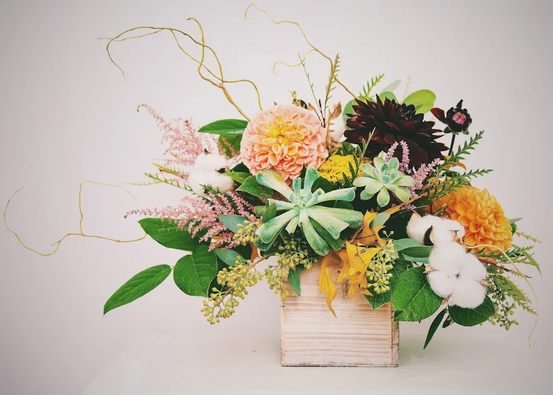 Spring floral arrangement with dahlias, succulents, cotton stems and greenery in a rustic wooden box vase