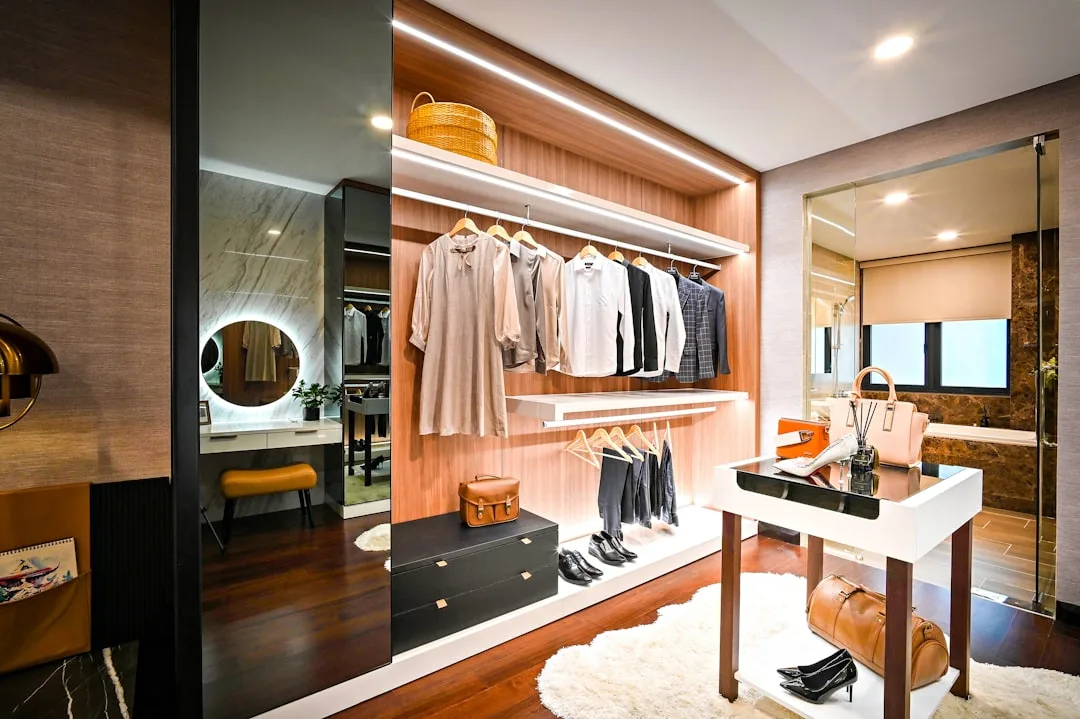 Luxury walk-in closet with LED strip lighting, hanging clothes, wood paneling, and upper shelf storage space