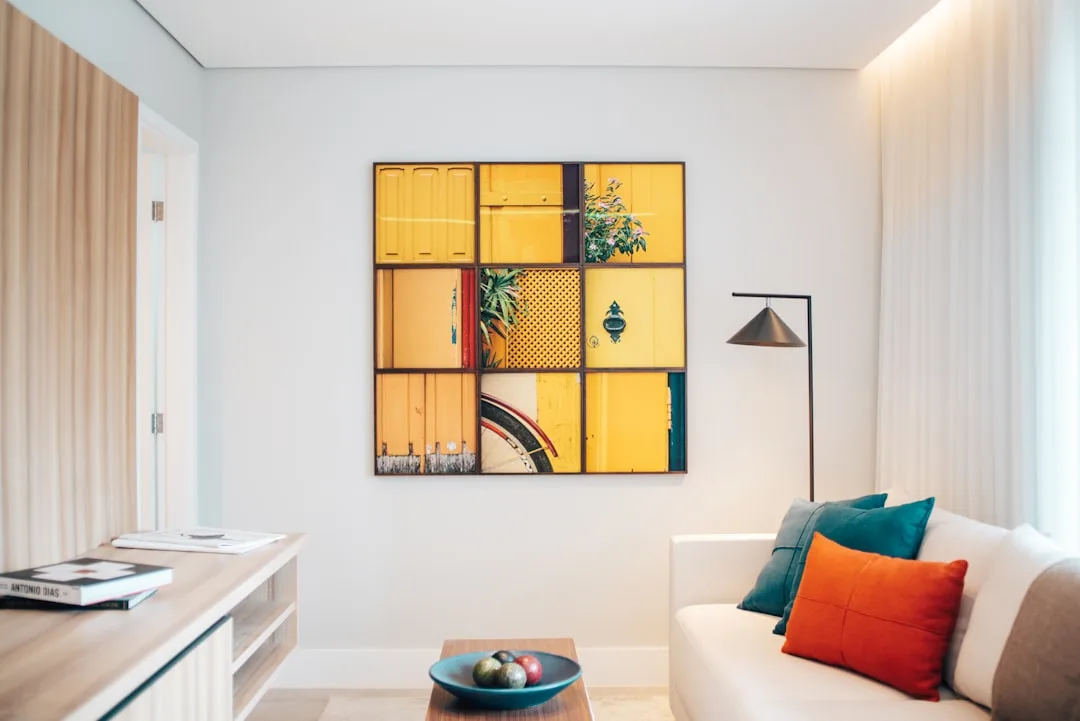 Modern living room with yellow grid wall art above sofa styled with teal and orange cushions and floor lamp