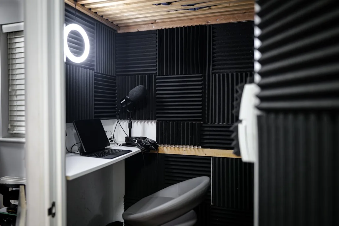 Small closet converted into a recording studio with acoustic foam panels, microphone, headphones, and ring light