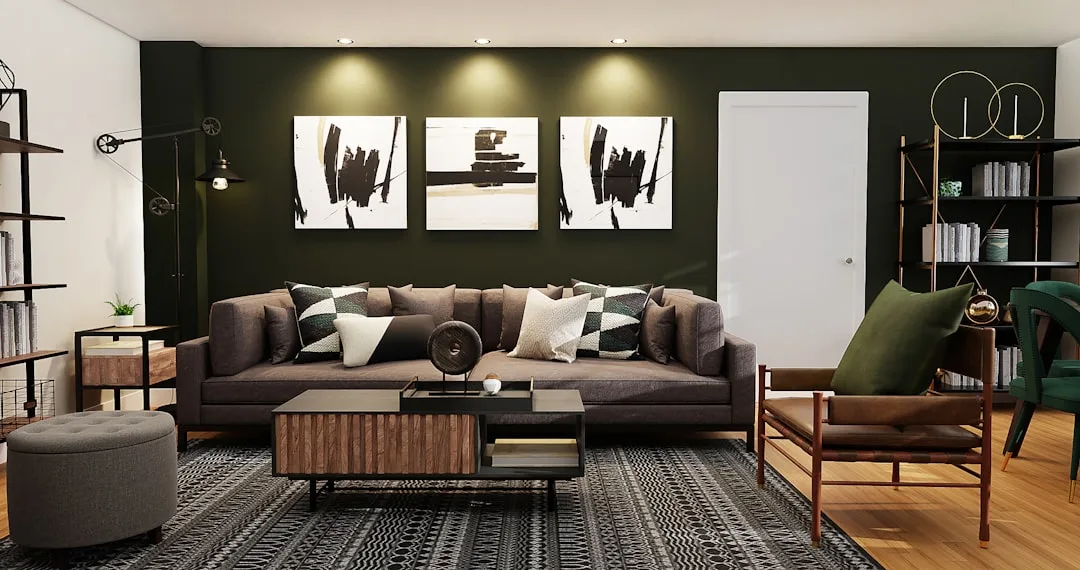 Modern living room with dark green accent wall, brown sofa, layered pillows, and minimal coffee table styling