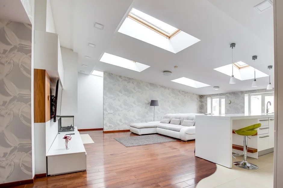 Modern open-plan living room with multiple skylights as centerpiece design feature and white sectional sofa