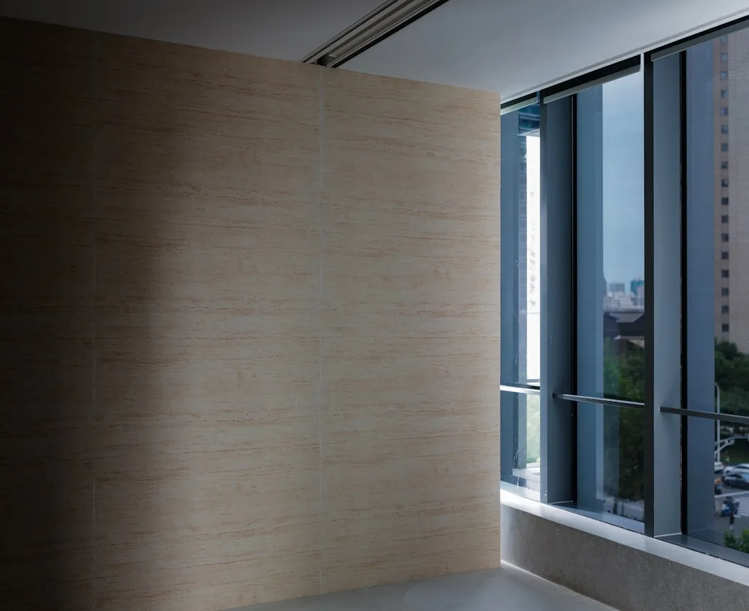 Travertine marble wall cladding panels in modern interior with floor-to-ceiling windows showing urban view