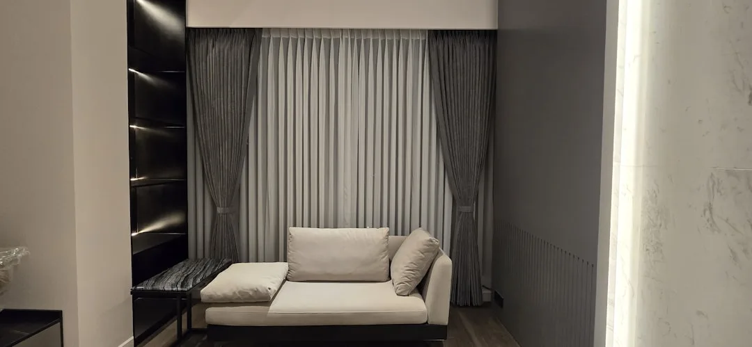 Modern dual-purpose reading nook with white chaise lounge sofa and gray curtains in contemporary living room