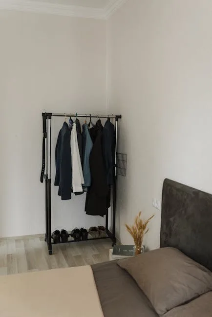 Freestanding black clothing rack with suits and jackets in small bedroom under 150 square feet storage solution