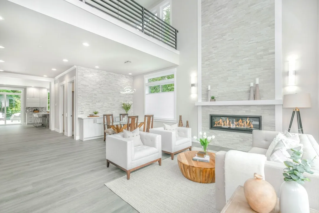 Open-plan modern living room with white furniture, stone fireplace, and flexible layout designed for timeless style
