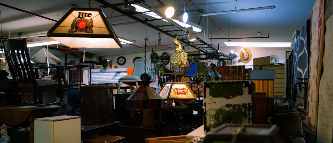 Cluttered antique thrift store interior filled with vintage furniture, stained glass lamps, and eclectic collectibles