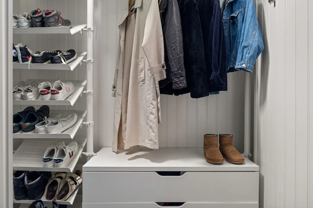 White built-in closet organizer with shoe rack shelves, hanging jackets, and drawer unit for homeowner storage